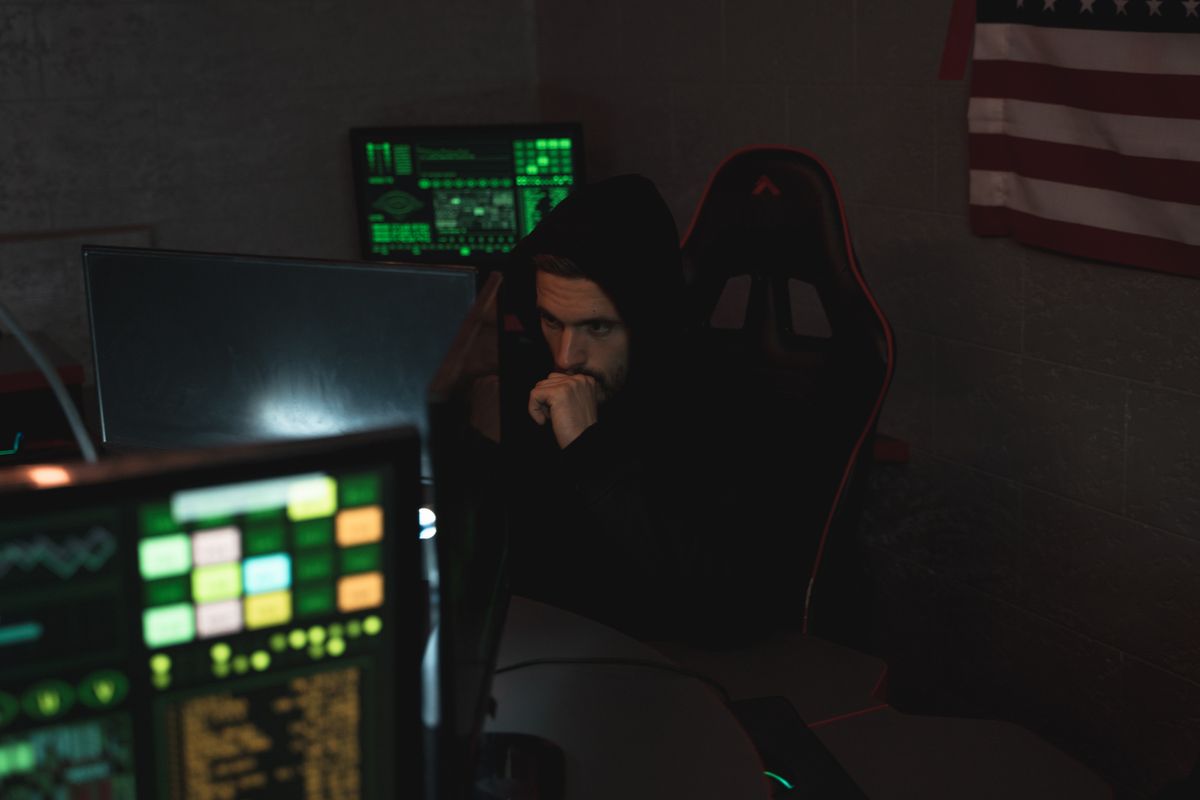 Cybersecurity specialist monitoring multiple screens in a dark room