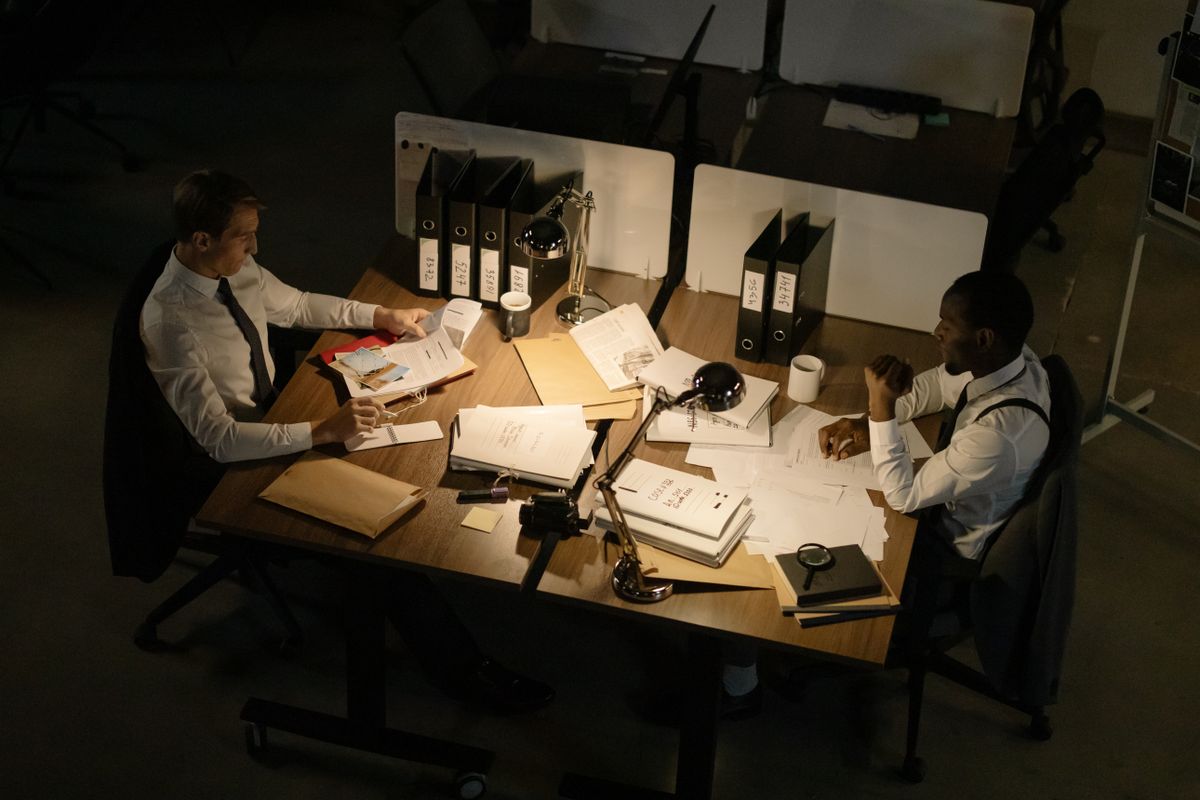 Two business people discussing documents in a dimly lit office