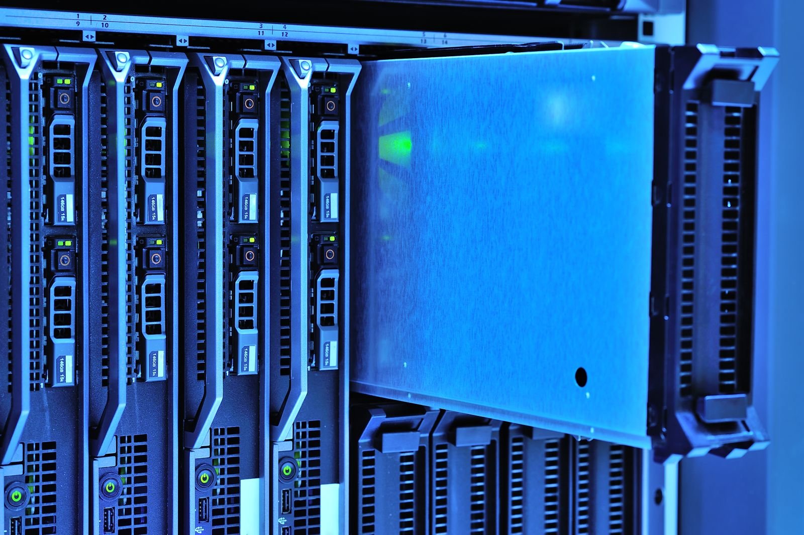 Cận cảnh các máy chủ dạng phiến trong tủ rack của trung tâm dữ liệu, một máy được kéo ra, dưới ánh đèn xanh lạnh